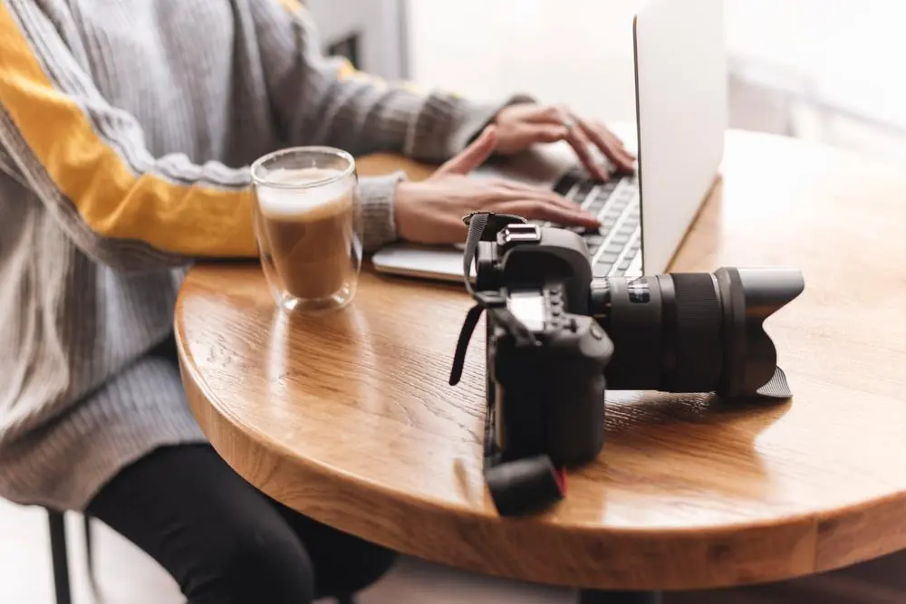 Freelancer working on a laptop with a camera on the table