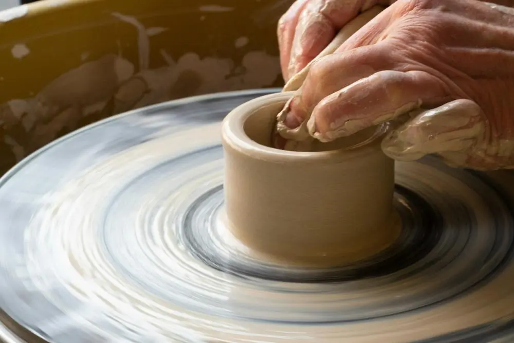 Hands shaping clay on a potter's wheel